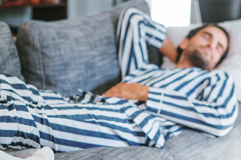 A man sleeping on a sofa in his striped pyjamas
