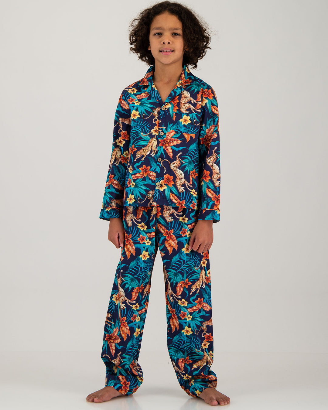 A boy wearing Long Pyjamas with a Jungle Cheetahs print on a navy background