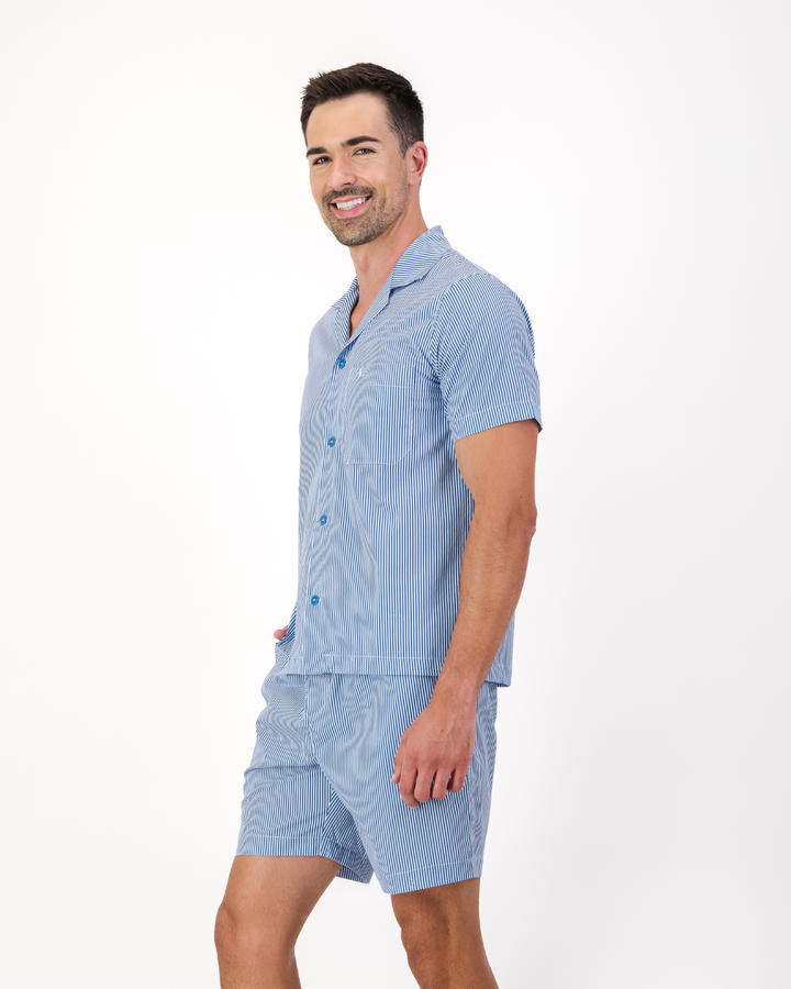 Man wearing blue and white striped organic cotton pyjama set featuring side pockets