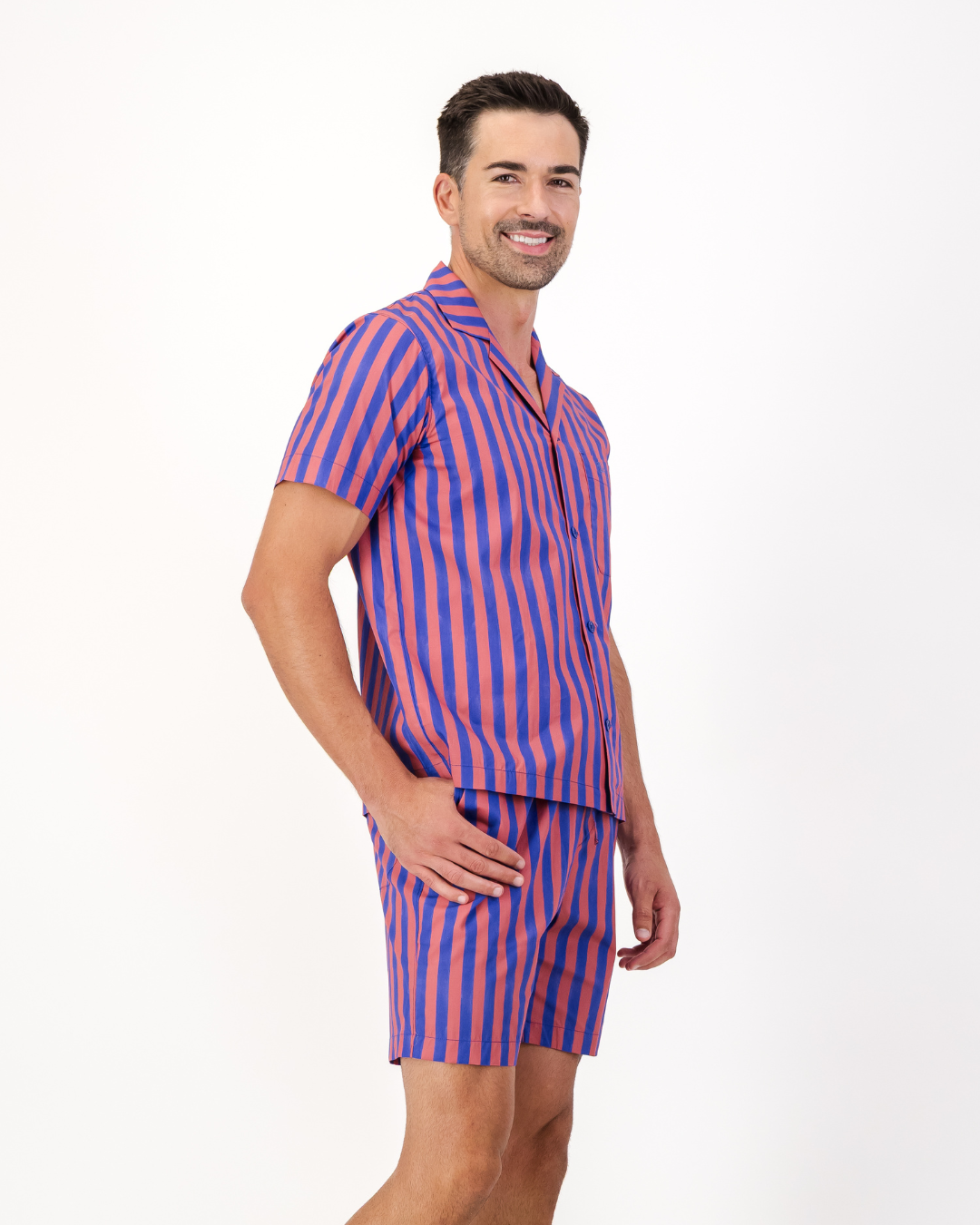 Man wearing red and blue striped organic cotton short pyjama set featuring side pockets