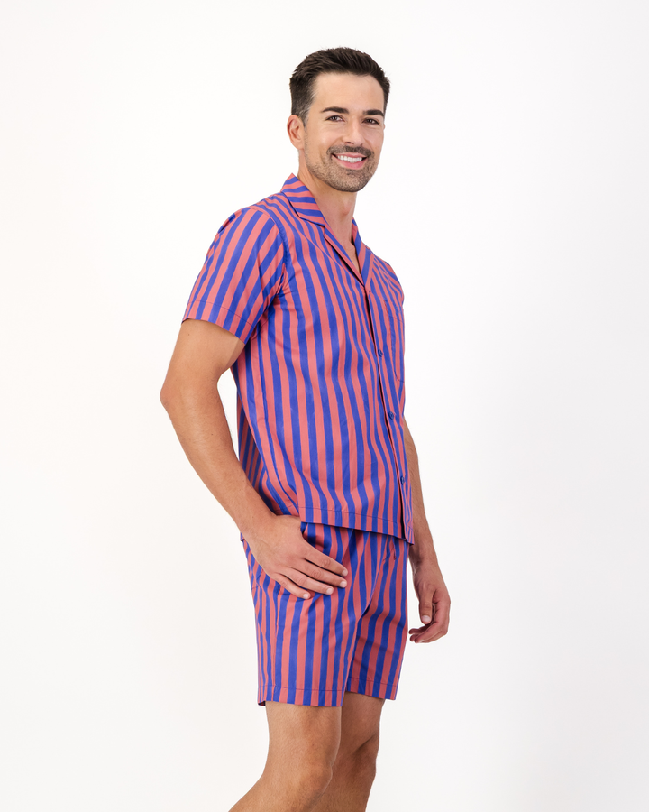 Man wearing red and blue striped organic cotton short pyjama set featuring side pockets