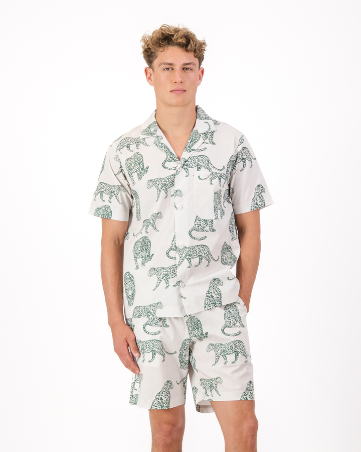 Man wearing a teal leopard print organic cotton pyjama set featuring side pockets