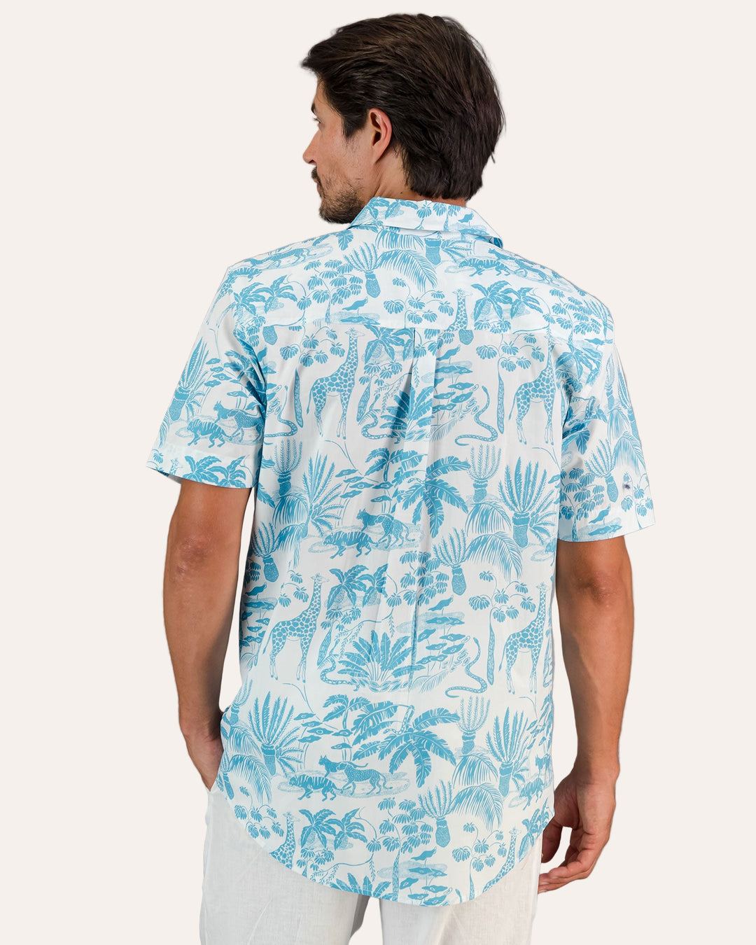 A rear view of a man wearing a Mens Holiday Shirt - Blue Mono Safari on White against a gray background