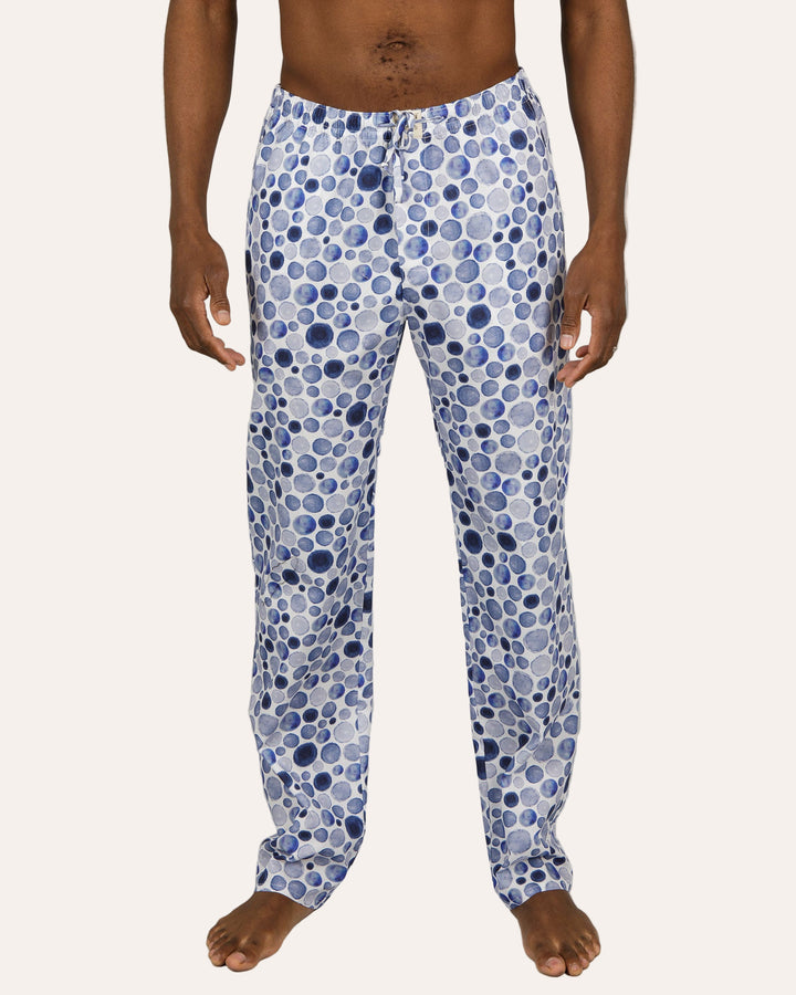 Man wearing blue polka dot pyjama pants on a grey background